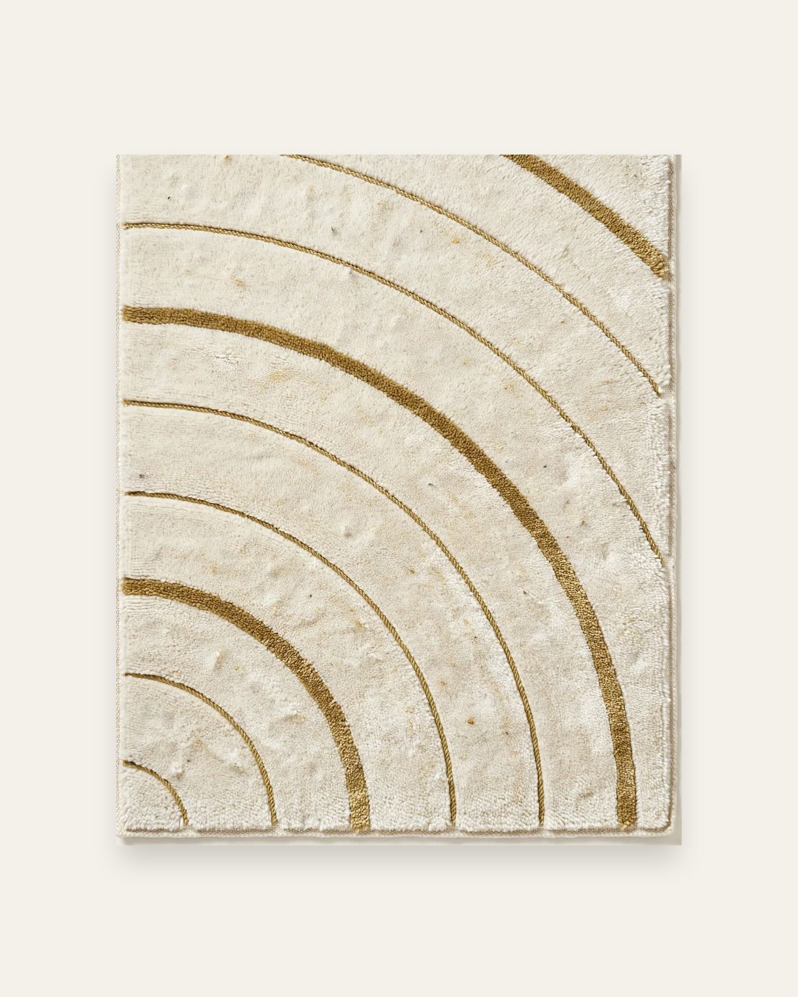 Kaiyo Arc rug, full view: antique-gold arcs sweeping from one corner of an ivory field